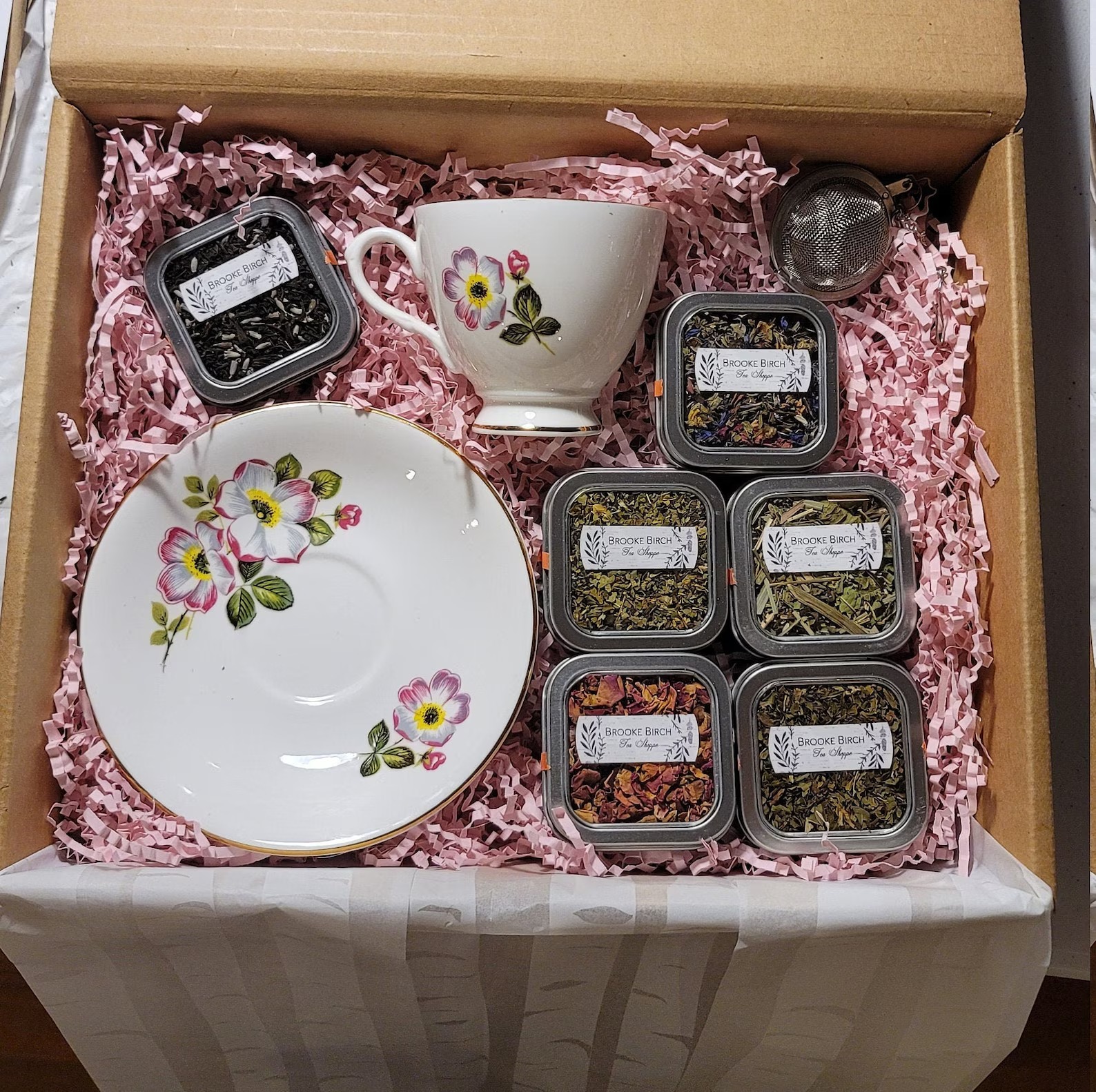 Kutija sa porcelanskom šoljom, tacnom, cediljkom i šest kutijica čaja u roze punjenju
